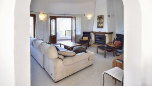 A living room with a sofa, armchairs, a fireplace, and a balcony. - Villa Clementina by Interhome (Pego)
