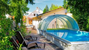 A swimming pool with a glass enclosure, surrounded by lounge chairs and a paved patio.