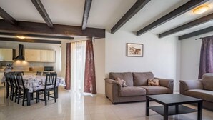 A spacious living area with a sofa, a coffee table, and a dining table with chairs. There is a kitchen visible in the background. - Dorijano by Interhome (Rabac)