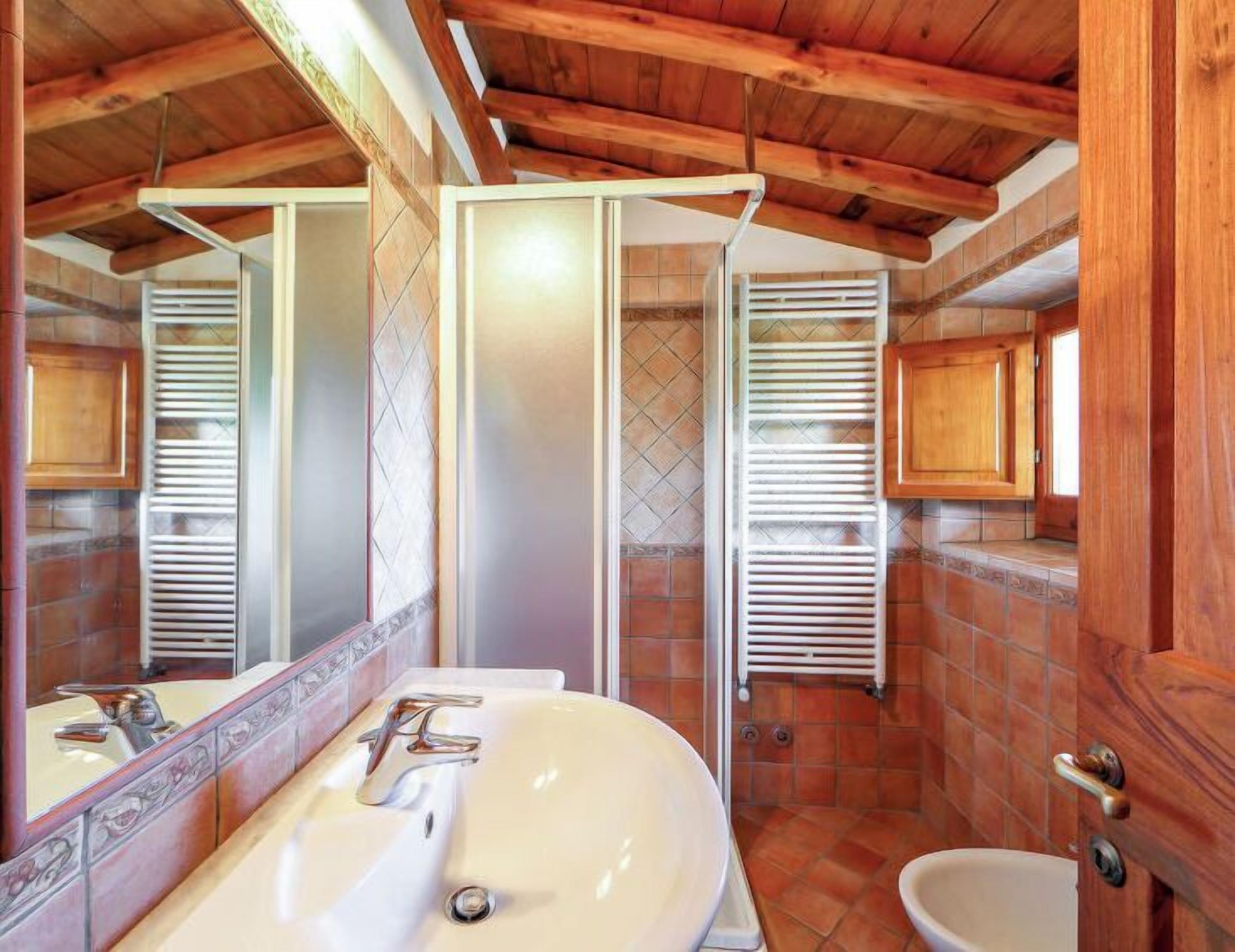 A bathroom with a white sink, a mirror, wooden cabinets, and a tiled floor.