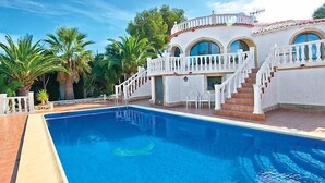 A pool area with a white building, a staircase, and palm trees. - Vacation home Vina by Interhome (Jávea)