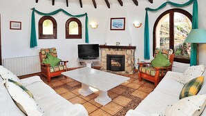 A cozy living room with a fireplace, comfortable seating, and a television. - Vacation home Vina by Interhome (Jávea)