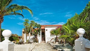 A stone pathway leading to a white building with a red-tiled roof, surrounded by tropical plants. - Vacation home Vina by Interhome (Jávea)