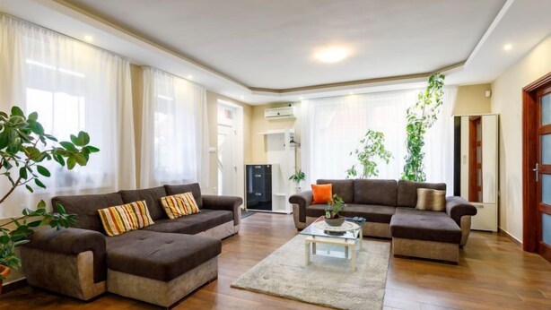 Amplia sala de estar con dos sofás, una mesa de centro y ventanas grandes con cortinas.