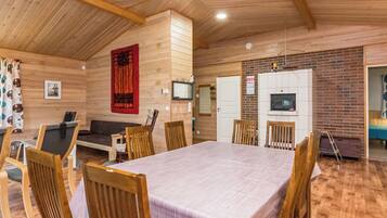 Un interior de madera con una mesa de comedor, sillas, un sofá y una chimenea.