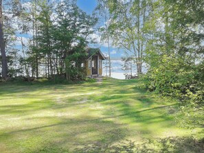 A cabin with a porch, surrounded by trees and a grassy area. - Aurinkoniemi by Interhome (Kesälahti)