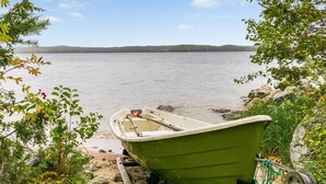 Un bote verde en un muelle, con un lago y un bosque al fondo.
