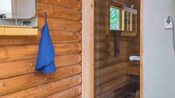A wooden cabin interior with a glass door leading to a bathroom.