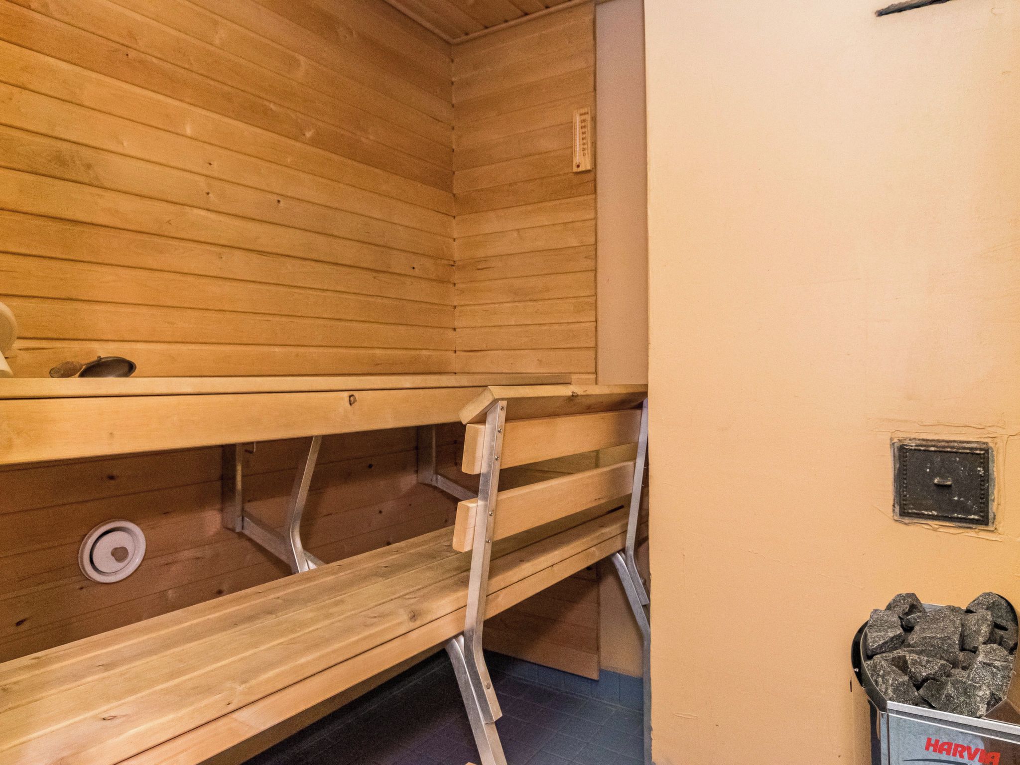 A sauna room with wooden benches and a metal grate on the floor.