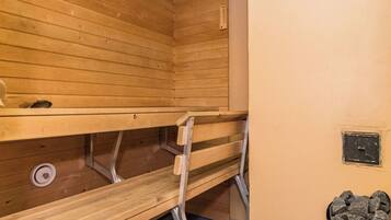 A sauna room with wooden benches and a metal grate on the floor.