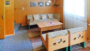 Ett mysigt rum med trägolv, en soffa, ett bord och två bänkar.