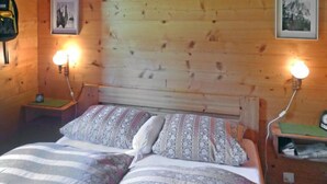 Ett rum med träpanel, en säng, två sängbord och två vägglampor.