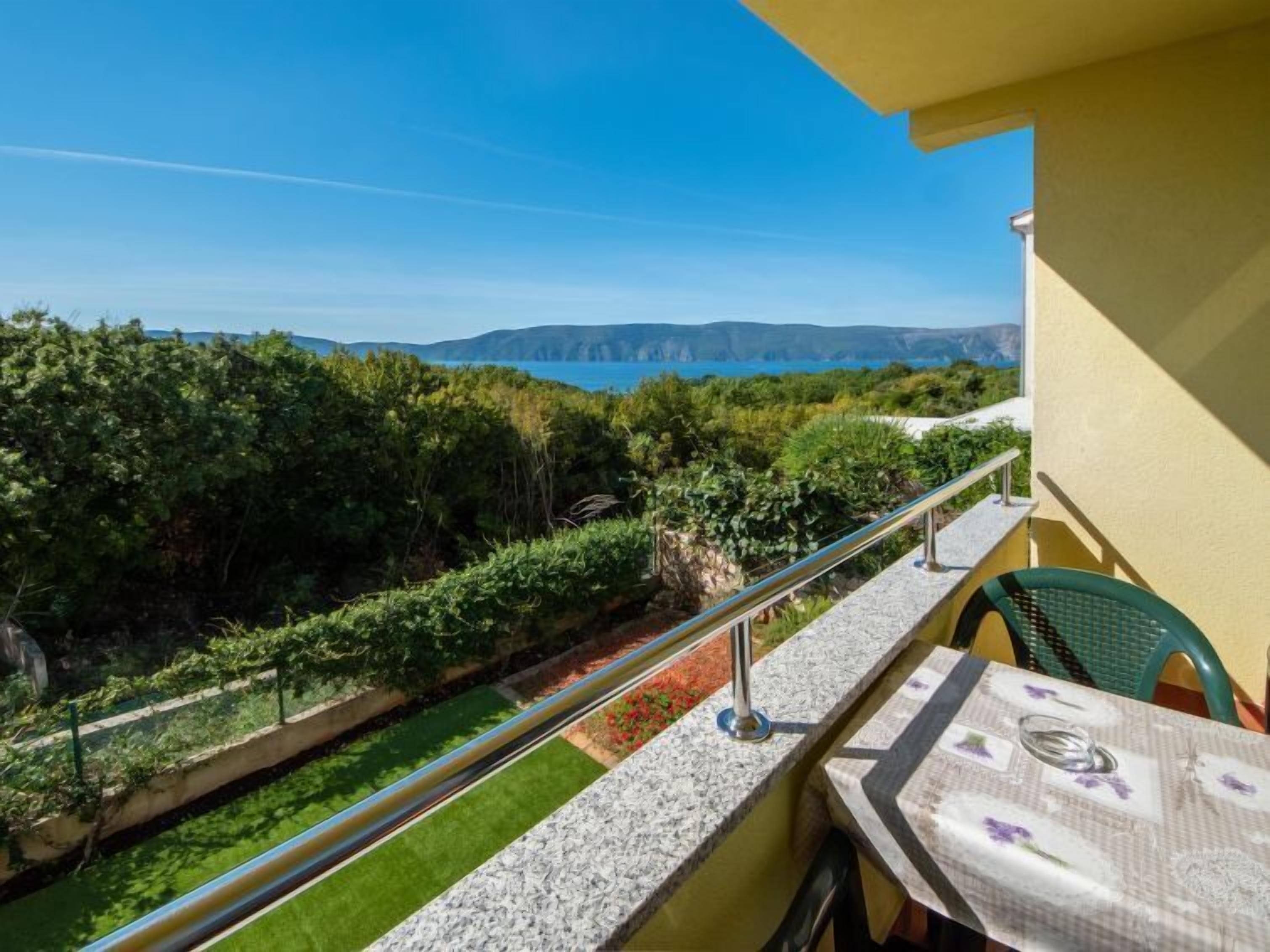 A balcony with a view of the sea and hills.