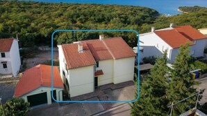 A coastal residential area with houses featuring red-tiled roofs and light-colored walls.