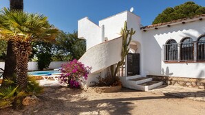Un edificio blanco con piscina, palmeras y un cactus.