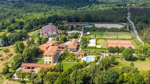 An aerial view of a residential area with a large house, tennis courts, and surrounding greenery. - Tipologia Trilocale by Interhome (Fucecchio)