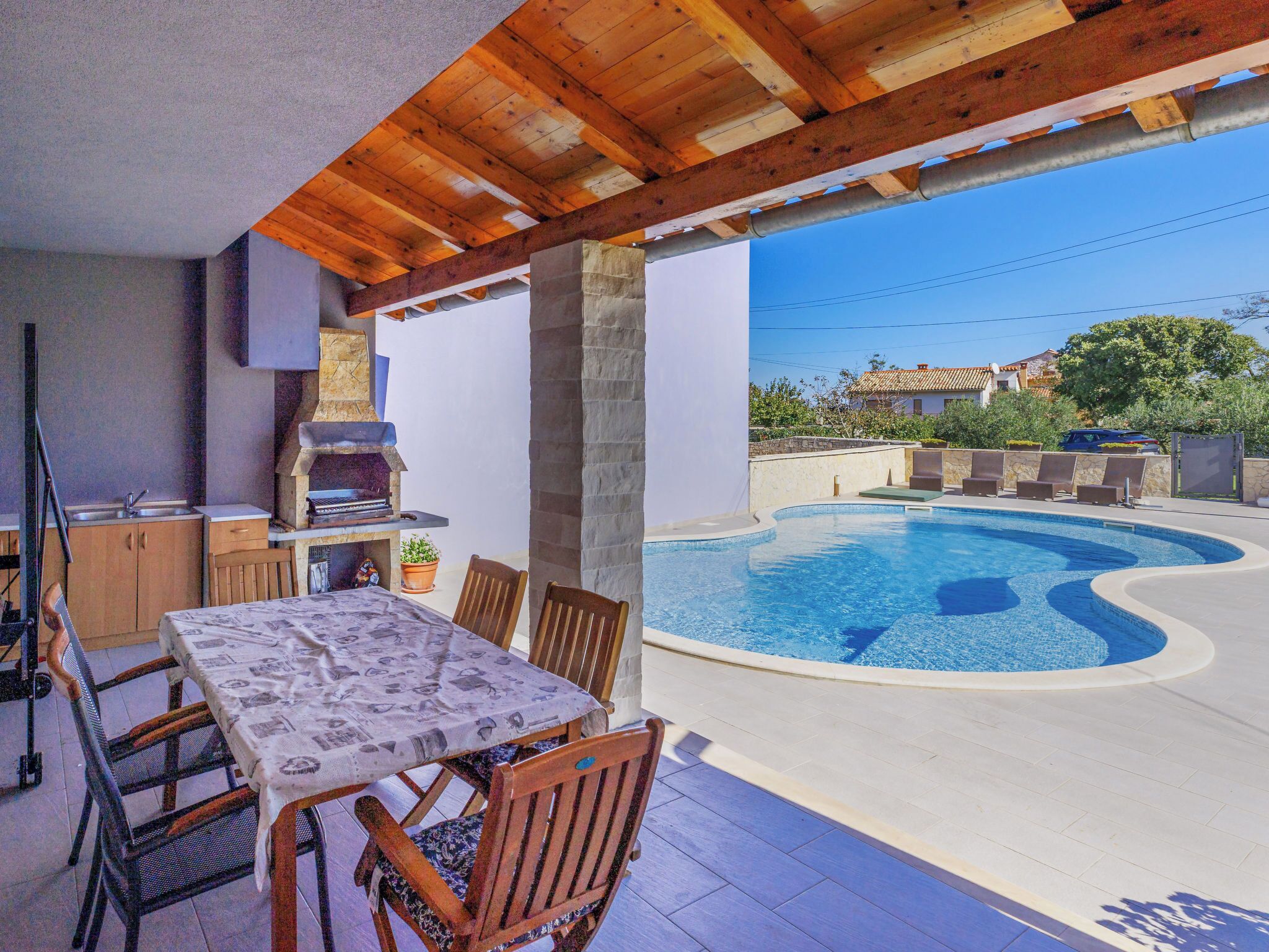 Un espacio al aire libre cubierto con piscina, una parrilla y una mesa de comedor con sillas.