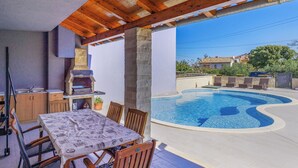 A covered outdoor area with a pool, a barbecue grill, and a dining table with chairs. - Mario 2 by Interhome (Pula/Krnica)