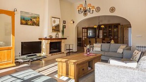 Un soggiorno con camino, divano, tavolino, TV e, sullo sfondo, una zona pranzo.