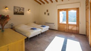 Una stanza con due letti, travi in legno al soffitto, un termosifone e una finestra vista.