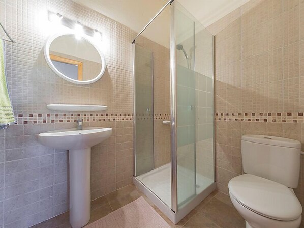 A bathroom with a glass-enclosed shower, a pedestal sink, and a toilet.