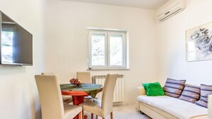 Ein kompakter Wohnbereich mit Essbereich, einer Couch und einem an der Wand befestigten Fernseher.