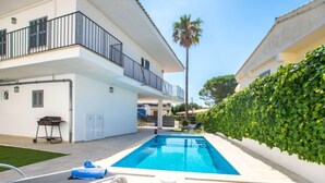 A modern pool area with a clear blue pool, lounge chairs, and a neatly trimmed hedge. - Gambaner by Interhome (Alcúdia)