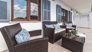 A balcony with wicker furniture, a glass table, and a view of the sky. - Gambaner by Interhome (Alcúdia)