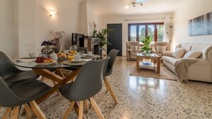 A modern living room with a dining area, featuring a round table with chairs, a sofa set, and a coffee table. - Gambaner by Interhome (Alcúdia)
