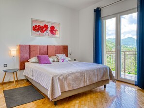 Relax in this serene bedroom with a large bed, bedside table, and stunning balcony view.