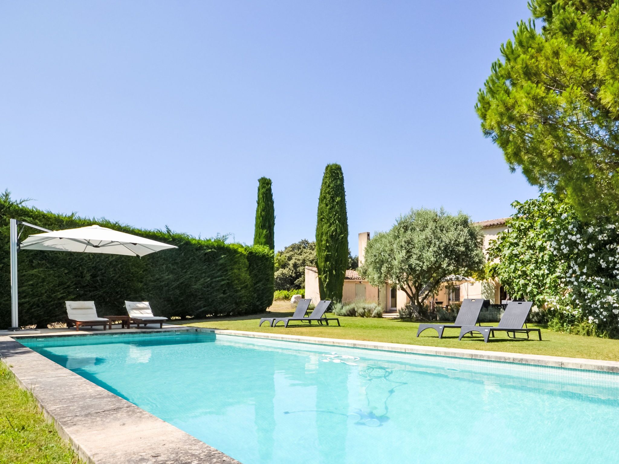 A swimming pool with lounge chairs and an umbrella.