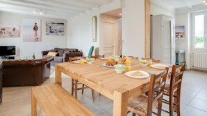 A dining area with a wooden table set for breakfast, a sofa, and a TV in the background.