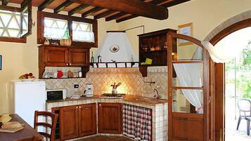 Una cucina con mobili in legno, zoccolo piastrellato, forno integrato e una finestra con tende.