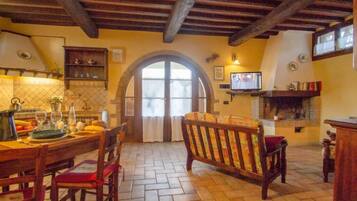 Una cucina rustica con pavimento piastrellato, mobili in legno e televisore a parete.
