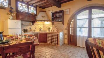 Una cucina rustica con travi in legno, zoccolo piastrellato e piano di lavoro in pietra.