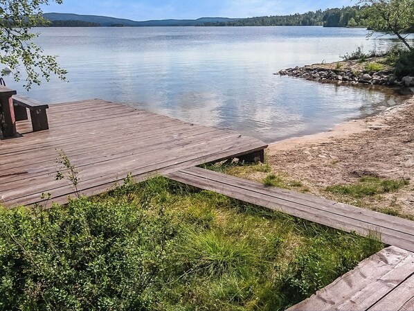 A wooden dock extending into a calm lake with a forested shoreline.