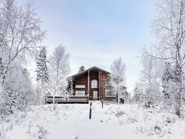 Una cabaña de troncos rodeada de árboles cubiertos de nieve.