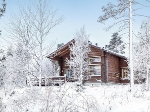 Una cabaña de madera rodeada de árboles cubiertos de nieve.