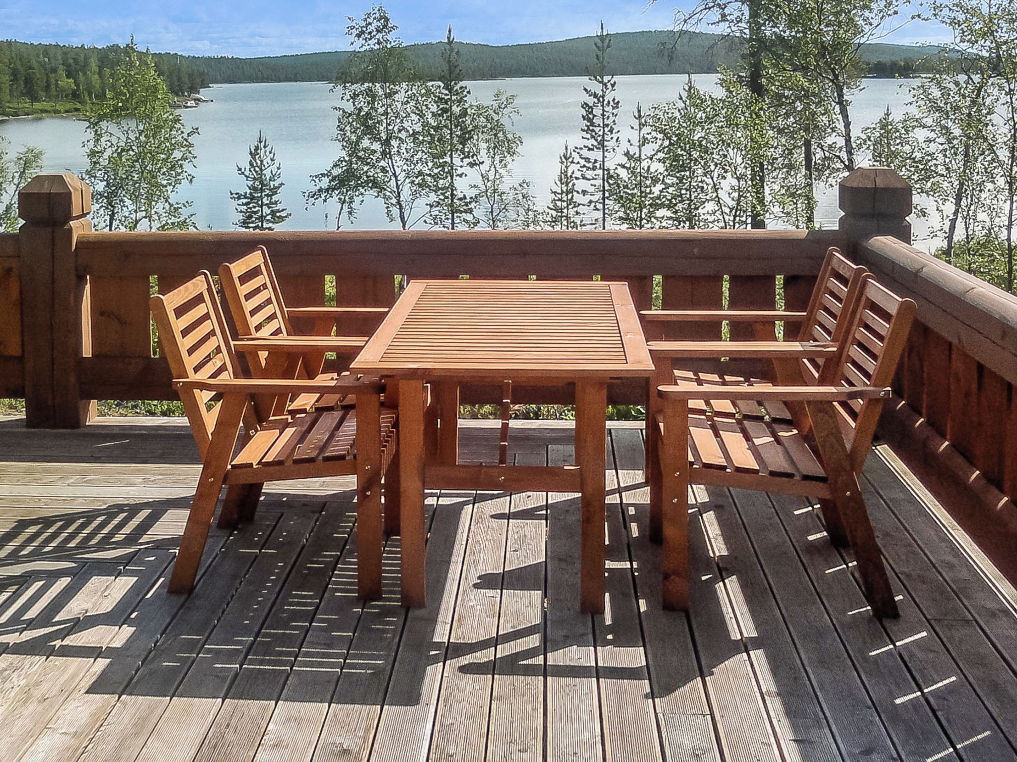 Puinen terassi, jossa on pöytä ja tuoleja, ja josta avautuu näkymä järvelle.