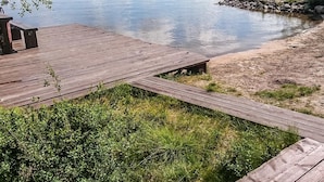 Une jetée en bois s’étendant sur un lac paisible, bordé d’une rive boisée.