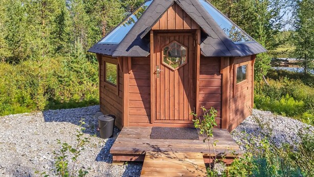 Une petite cabane en bois, dotée d’un toit en pente, d’une porte centrale et d’une fenêtre sur la façade.