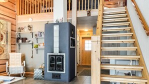 Un intérieur de chalet chaleureux avec une cheminée, un escalier en bois et un espace aménagé en mezzanine.