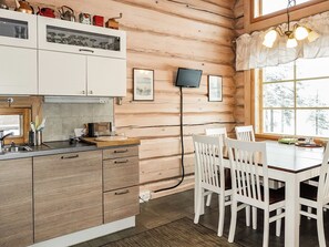 Un interior de madera con una zona de cocina, una mesa de comedor, sillas y un televisor montado en la pared.