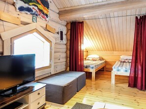 A cozy cabin room with a television, a small seating area, and two beds. - Aamunkoi by Interhome (Inari)