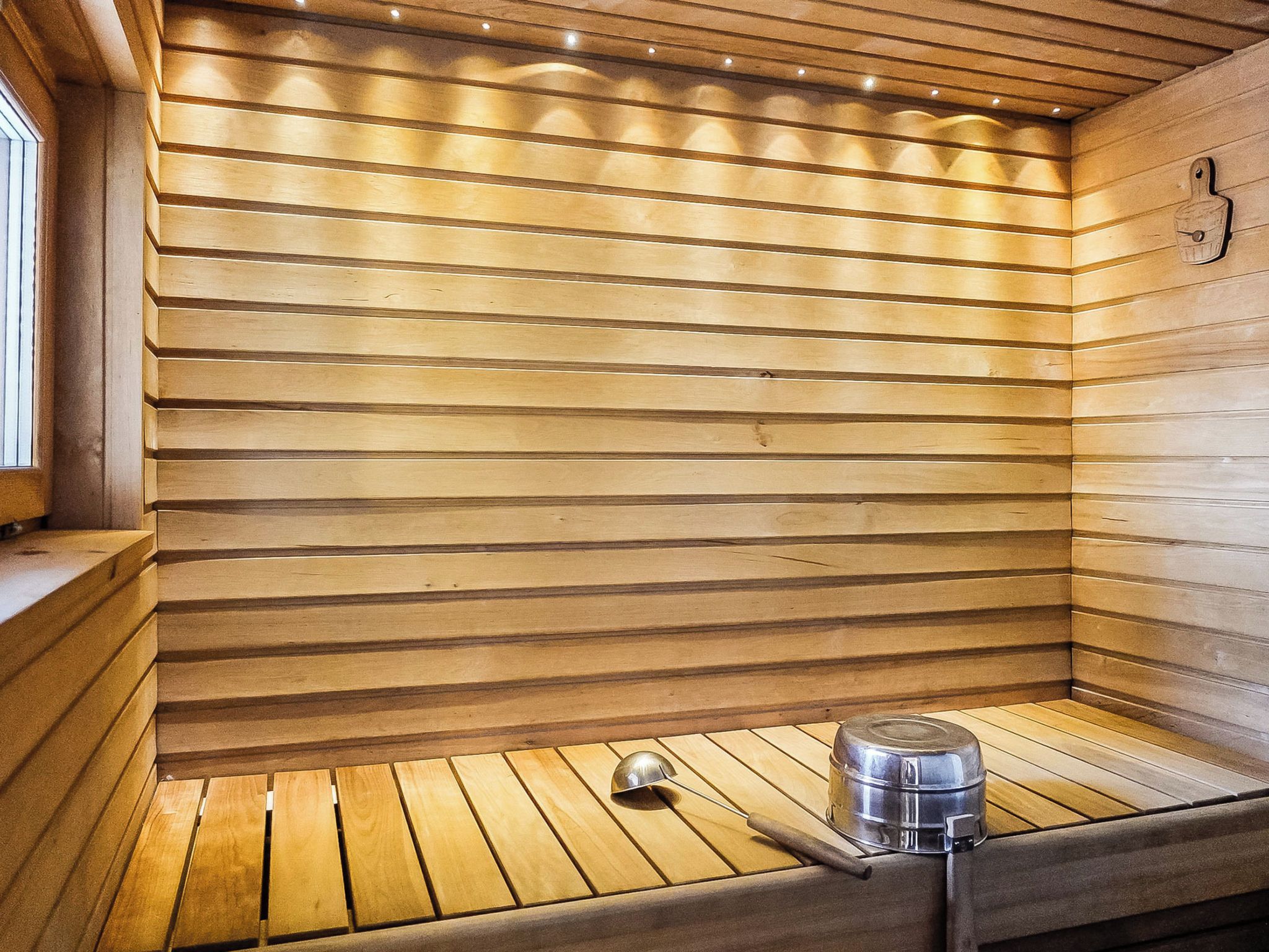 Una sauna con listones de madera en las paredes y un banco de metal.