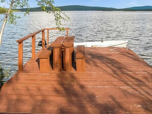 Un muelle de madera se extiende hacia un lago tranquilo donde una embarcación está amarrada al final.