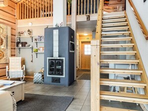 Una habitació acollidora amb una llar de foc, una escala de fusta i una biblioteca.