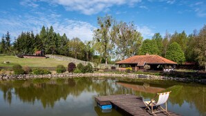 A tranquil lakeside setting with a wooden dock, a chair, and a small building with a red roof. - Osada Ulnowo by Interhome (Grunwald)