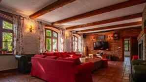 A cozy living room with a red sofa, wooden beams, a fireplace, and a TV on the brick wall. - Osada Ulnowo by Interhome (Grunwald)