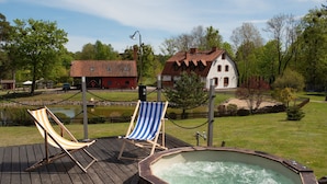 A wooden deck with two striped lounge chairs and a hot tub. - Osada Ulnowo by Interhome (Grunwald)